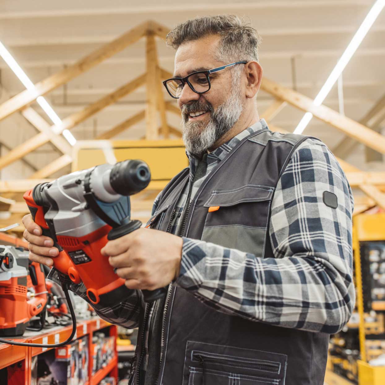 Small business owner examining a power drill in a hardware store.