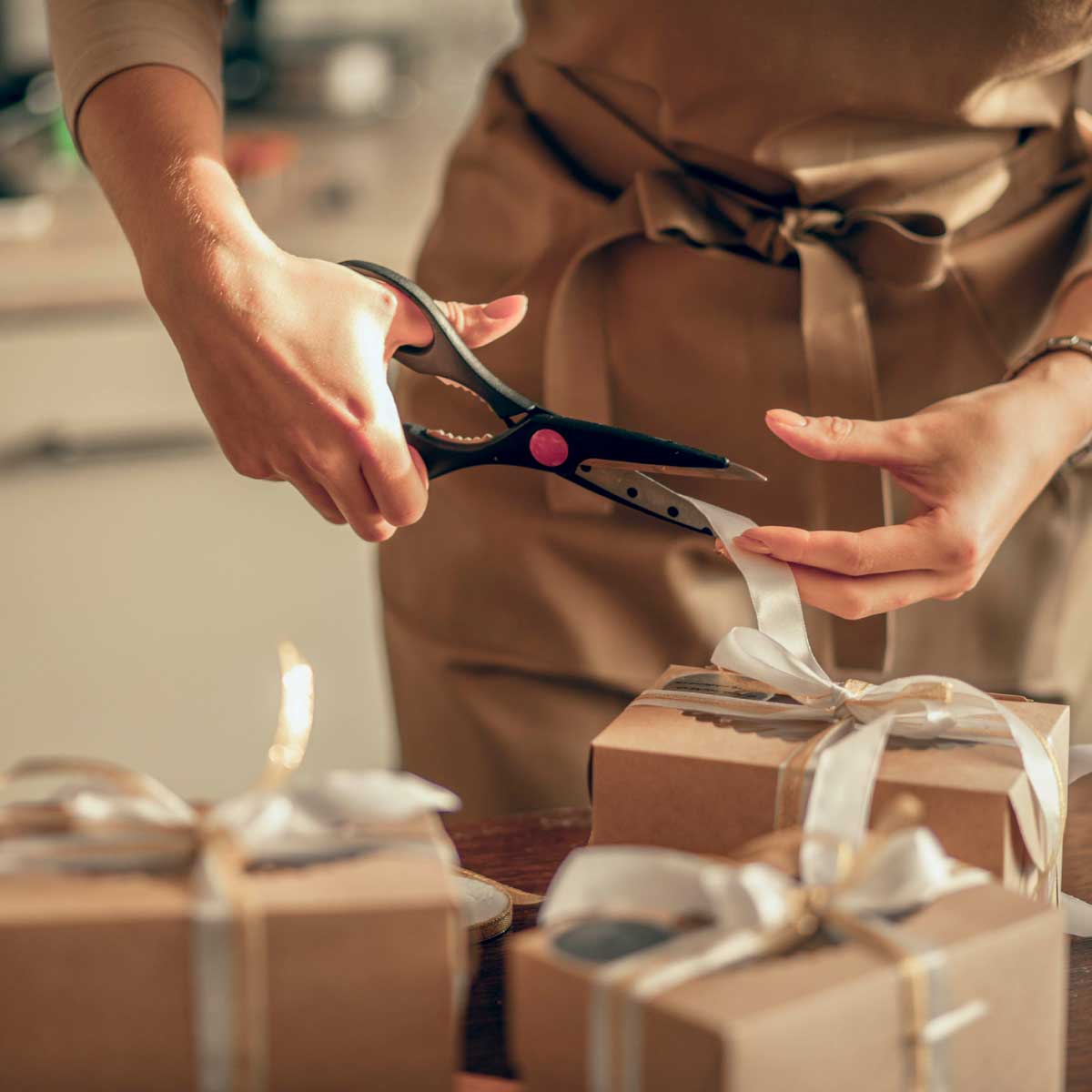 Person in apron cutting the ribbon on gift box