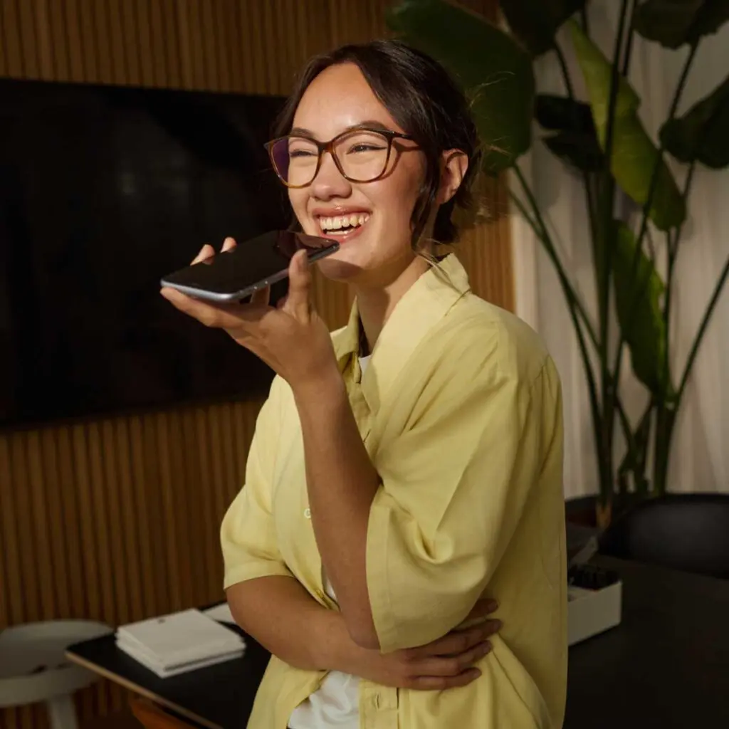 Young female business owner speaks on phone recording voice note