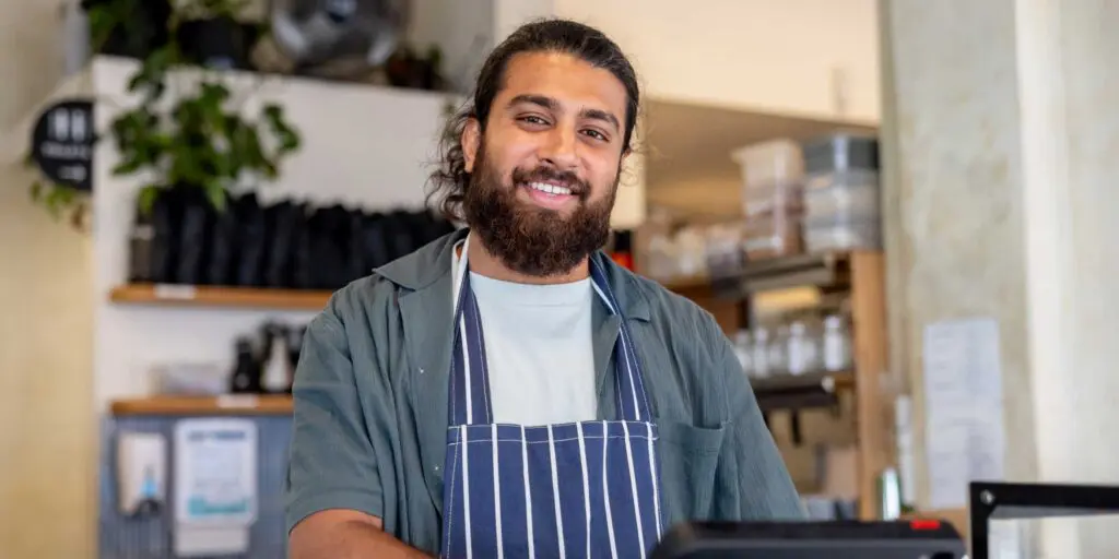 Small business owner smiling behind till