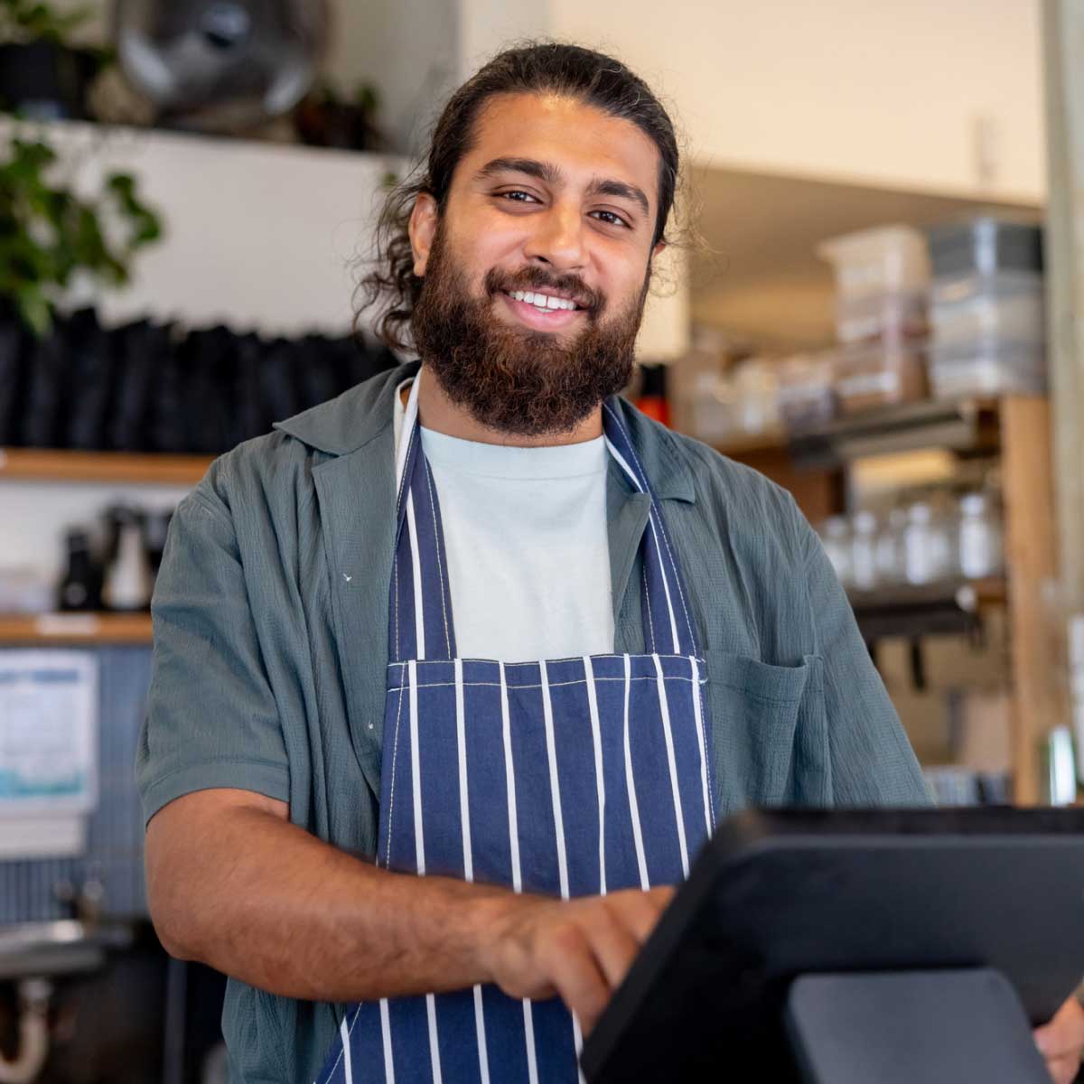 Small business owner smiling behind till