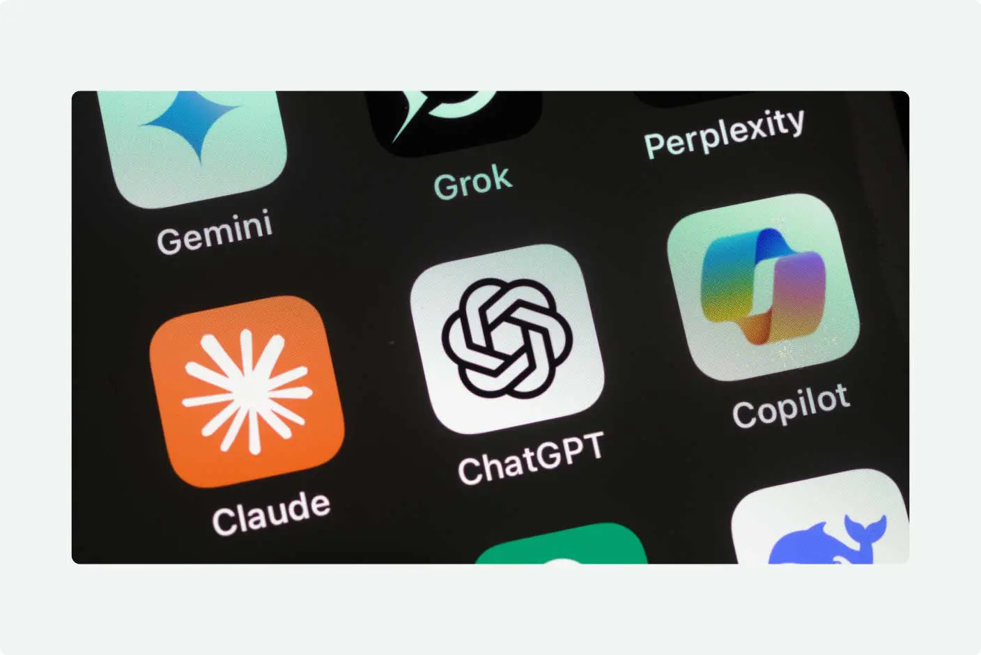 Close-up of a smartphone screen showing AI app icons, including Gemini, Grok, Perplexity, Claude, ChatGPT, and Copilot, arranged on a dark background.